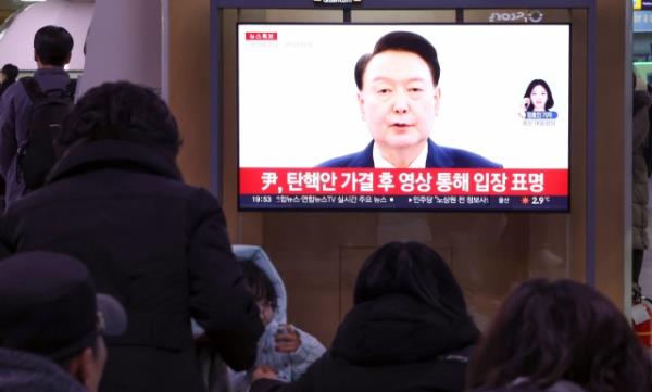 People watch as President Yoon Suk Yeol delivers an address Saturday after the Natio<em></em>nal Assembly voted to impeach him. (Yonhap)
