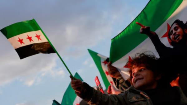 A child holds a flag adopted by the new Syrian rulers, as people gather during a celebration called by Hayat Tahrir al-Sham (HTS) at the Umayyad Square, after the ousting of Syria's Bashar al-Assad, in Damascus, Syria, December 20, 2024. Photo: REUTERS/Ammar Awad/ File Photo