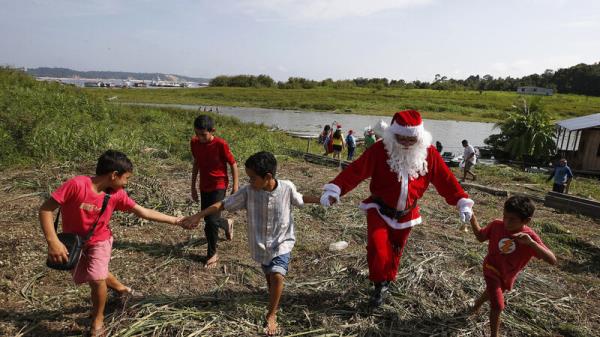 Santa braves sticky heat of Amazon jungle to bring gifts to children