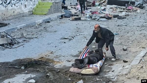 FILE - A Palestinian man uses a mattress to pull away a victim following Israeli strikes around the Kamal Adwan Hospital in Beit Lahiya in the northern Gaza Strip on Dec. 6, 2024.