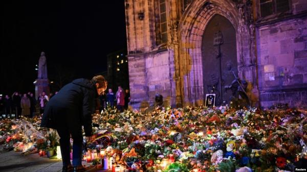A woman bends to place a tribute with flowers and candles left near the 'Alter Markt' Christmas market, wher<em></em>e a man drove a car into the crowd through an emergency exit route on Friday evening, in Magdeburg, Germany, Dec. 22, 2024. 