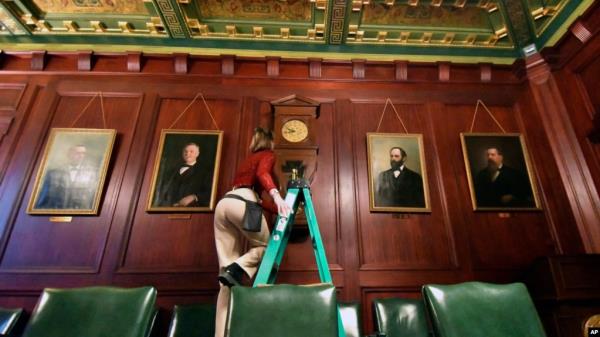 Bethany Gill climbs a ladder to wind a clock in a Pennsylvania Senate hearing chamber, in Harrisburg, Pennsylvania, Dec. 13, 2024. It's one of 273 clocks in Pennsylvania's ornate state Capitol complex buildings that must be wound by hand.