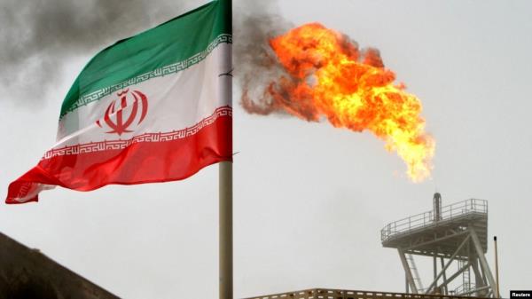 FILE - A gas flare on an oil production platform is seen alo<em></em>ngside an Iranian flag in the Gulf, July 25, 2005. On Dec. 19, 2024, the U.S. sanctio<em></em>ned three vessels involved in the trade of Iranian petroleum and petrochemicals.