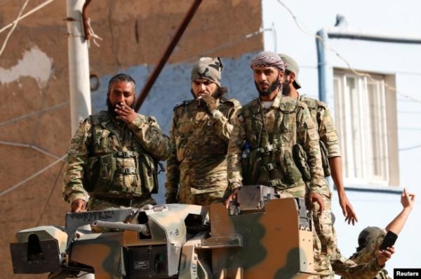 FILE - Members of Syrian Natio<em></em>nal Army, known as Free Syrian Army, stand on top of an armored vehicle in the Turkish border town of Ceylanpinar in Sanliurfa province, Turkey, Oct. 11, 2019.