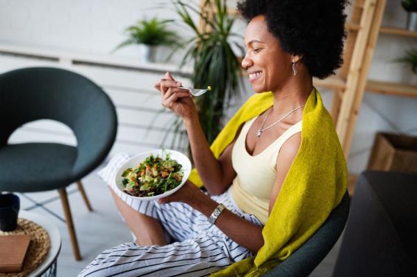 A young woman laughing, eating salad