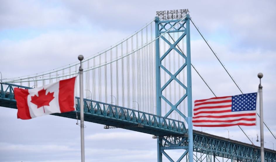 Canadian and American flags fly near the Windsor-Detroit Ambassador Bridge