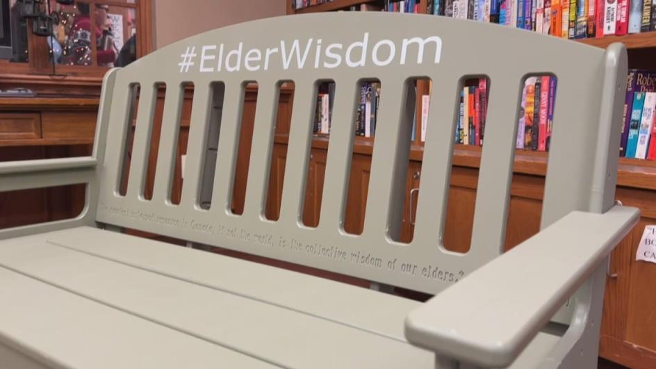 A light green bench has #ElderWisdom in white letters written on the back of it. 