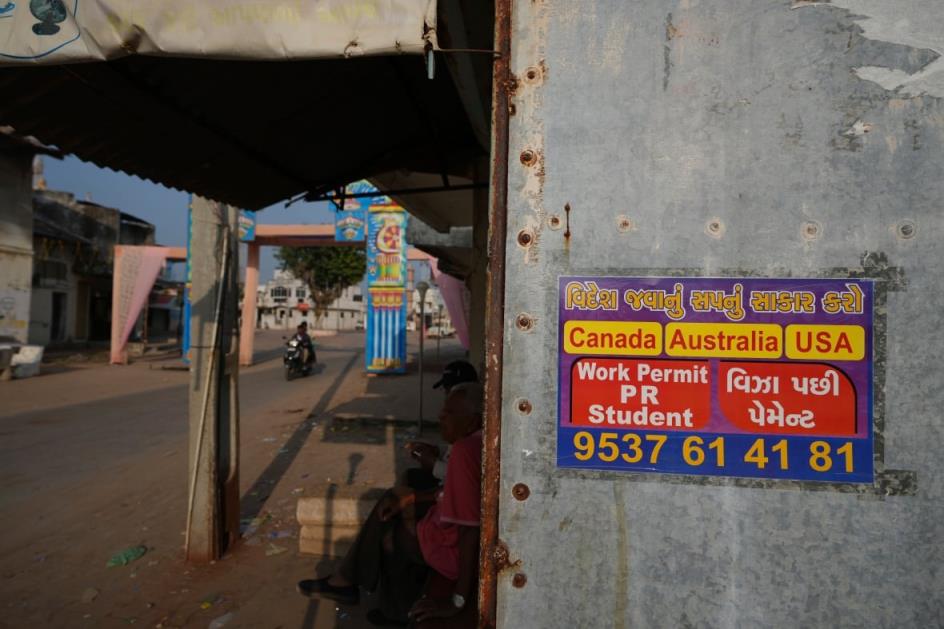 A poster on the exterior wall of a store advertises working and study visas.