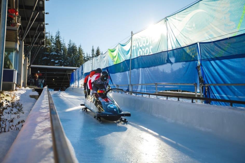 People are in a bobsled going down a track. 
