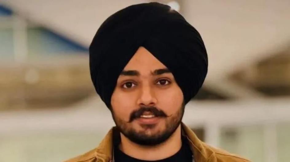 A man with facial hair wearing a black turban smiles for the camera. 