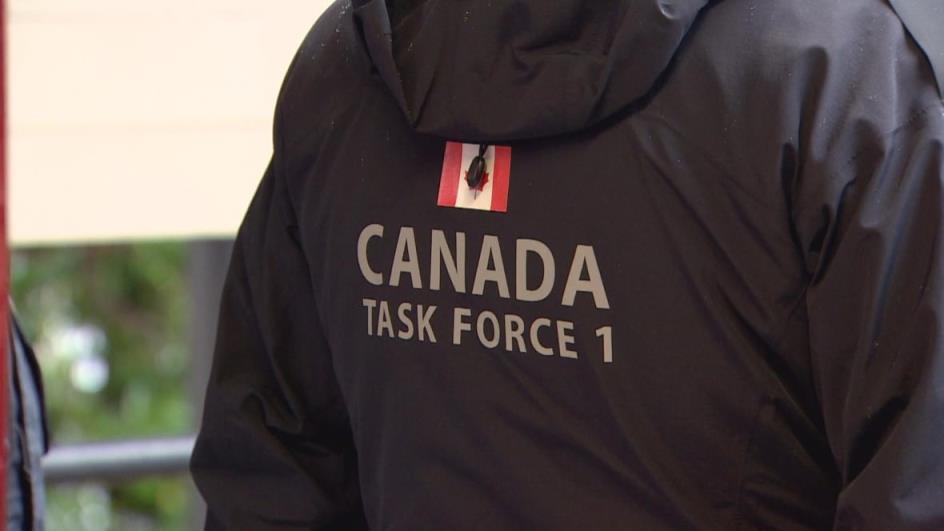A person wears a jacket with a Canada flag and the words 'Canada Task Force 1' on the back.