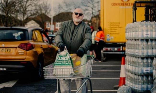 Roger Brown standing in a car park with a trolley and shopping bags
