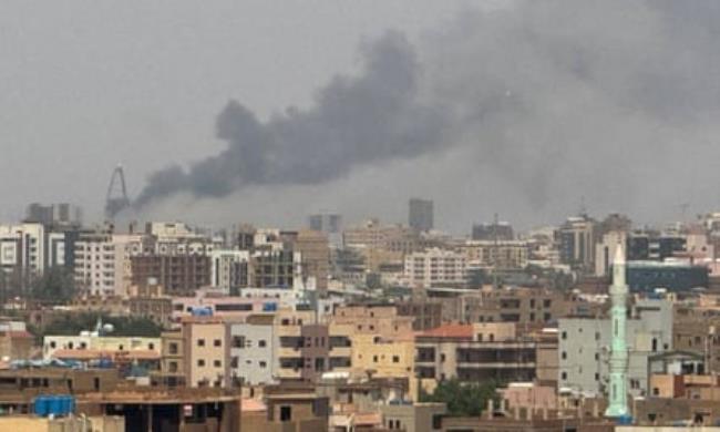 Wide view over buildings in Khartoum. Smoke rises into the sky in the background