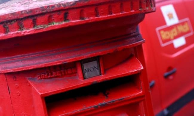 A post box stands in front of a Royal Mail van