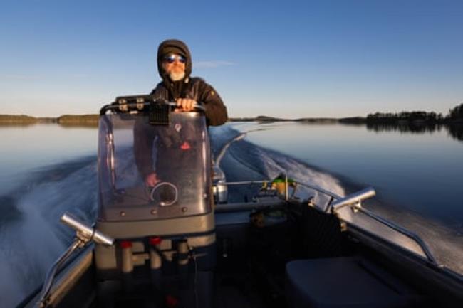 A man steers a motor boat on a lake