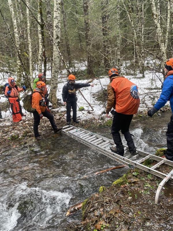 Rescuers cross a stream looking for the two missing Sasquatch hunters. 