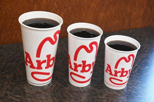 Three different sizes of soda cups - small, medium, and large, displayed at an Arby's restaurant in Queens, New York.