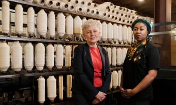 Two women standing in front of cotton mill machinery
