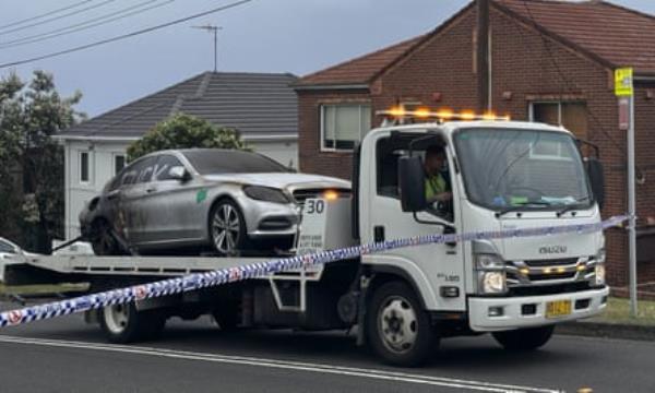 A burnt-out car with antisemitic graffiti is towed away 