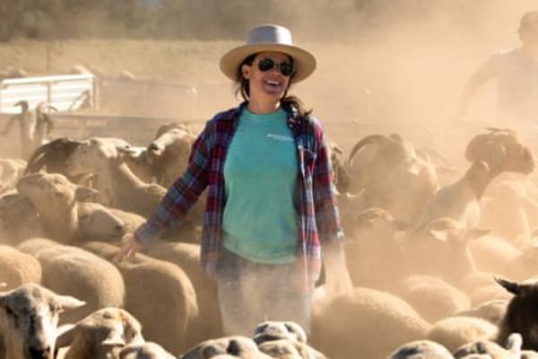 A woman standing in the midst of a herd of sheep
