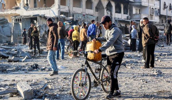 A man walks with a jerrycan balanced on a bicycle through debris at the site of Israeli bombardment on a residential block in Jalaa Street in Gaza City on January 14, 2025 amid the o<em></em>ngoing war in the Palestinian territory between Israel and Hamas. (AFP)