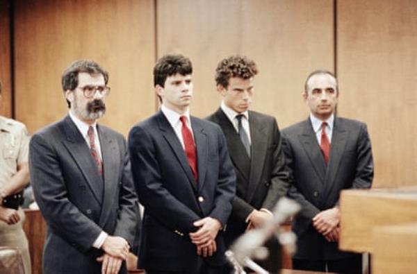 four men in suits standing in a court room together with their hands folded
