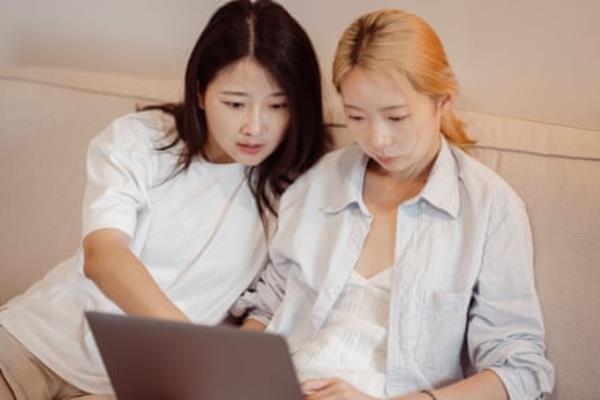 Women sharing ideas while using a laptop on the couch