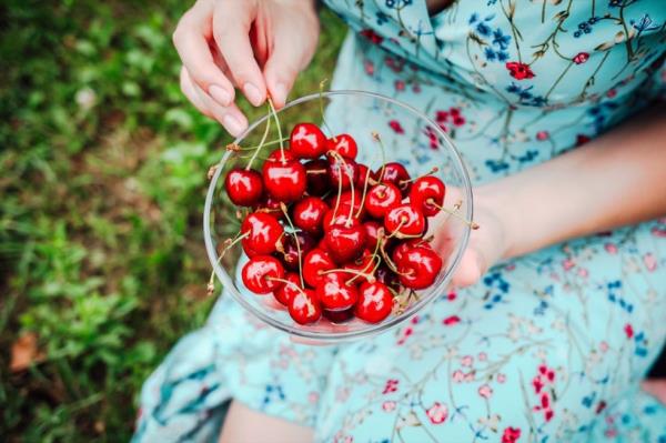 A woman eating from a bowl of cherries
