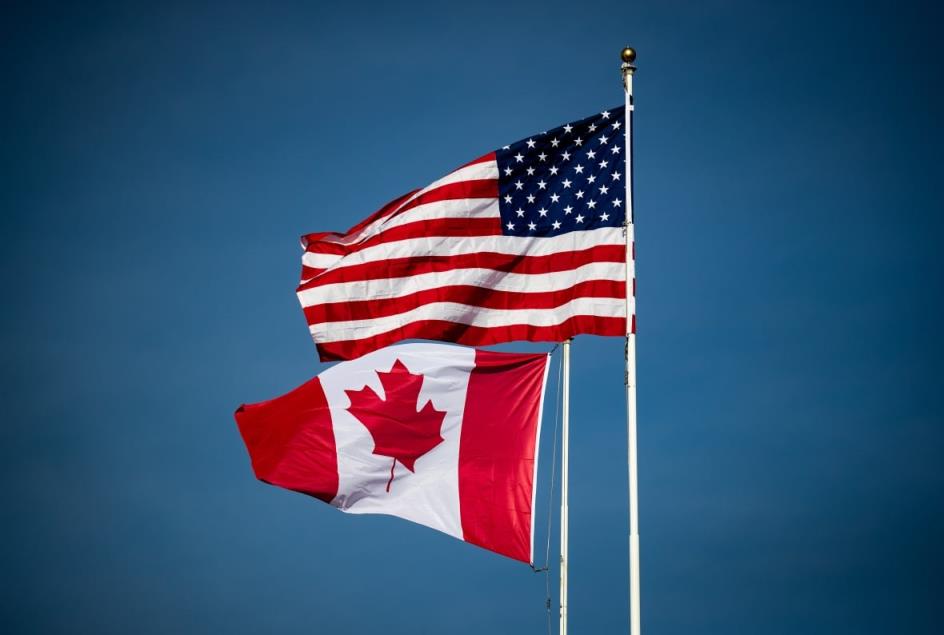 canada and U.S. flags blowing in the wind