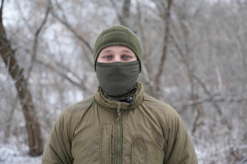 A soldier with blue eyes and a mask covering the lower half of his face looks at the camera.