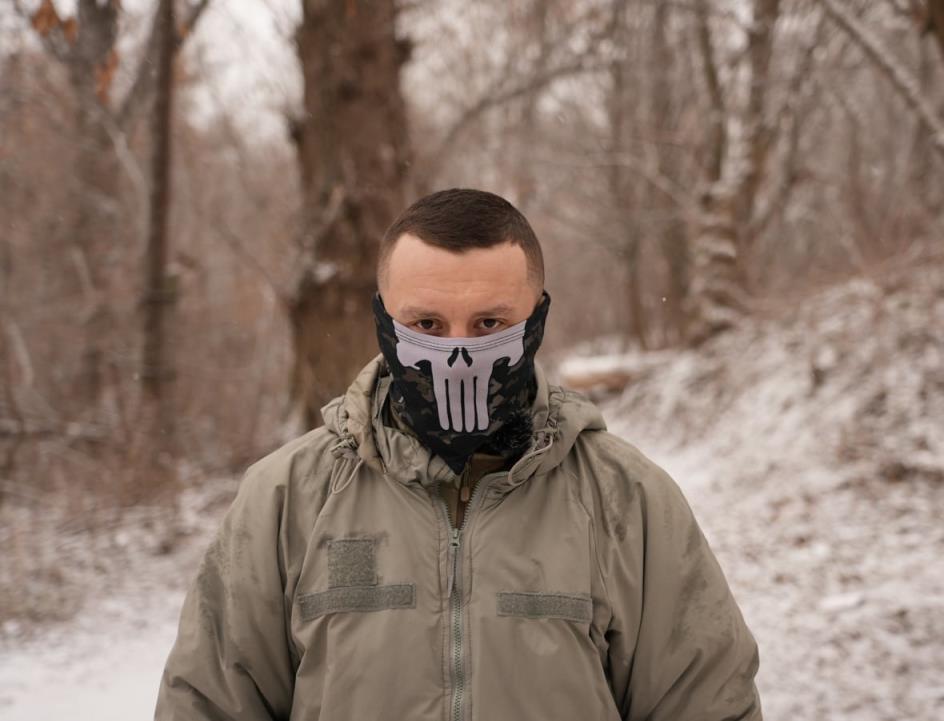 Man with mask covering half of his face looks at camera.