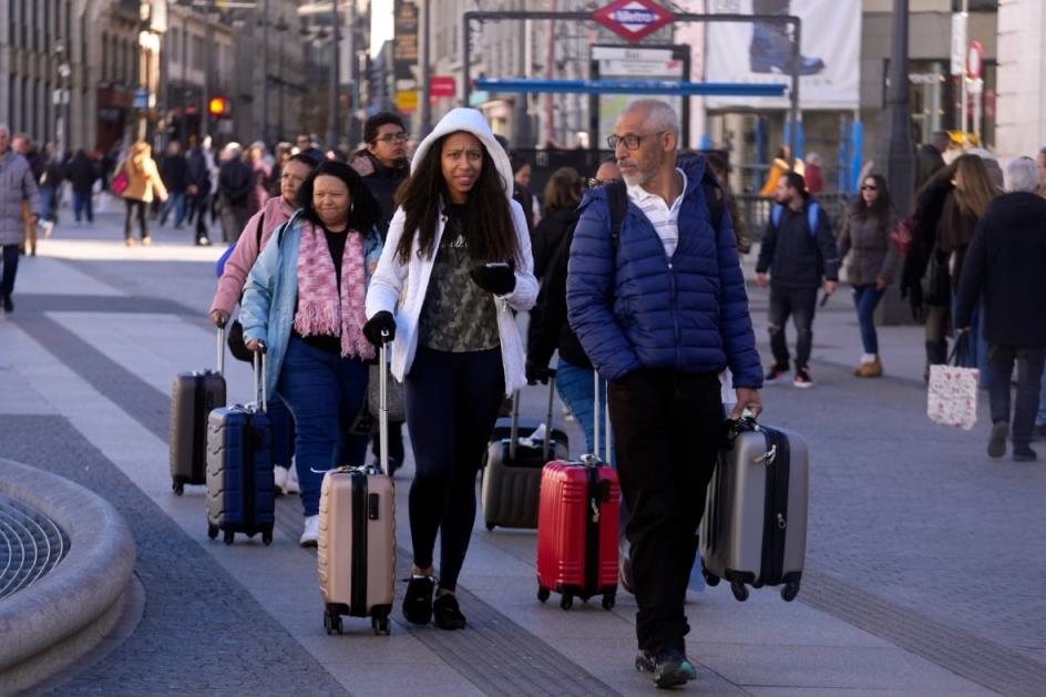 People with suitcases walk through a  city