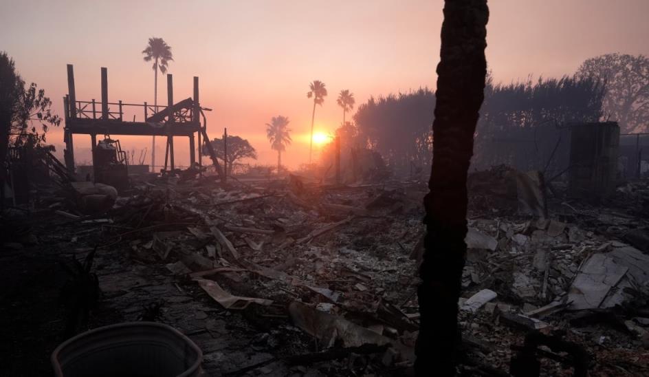 ashes and rubble wher<em></em>e a building o<em></em>nce stood. there are palm trees and orange skies in the background.
